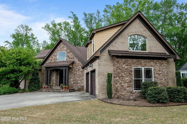 craftsman-style house featuring a front yard, an attached garage, stone siding, and driveway