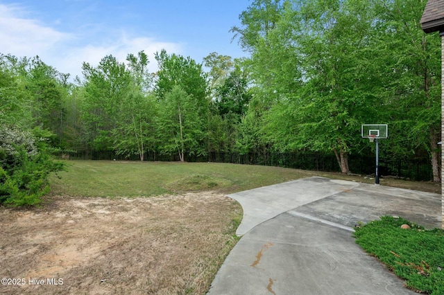view of yard featuring fence and basketball hoop