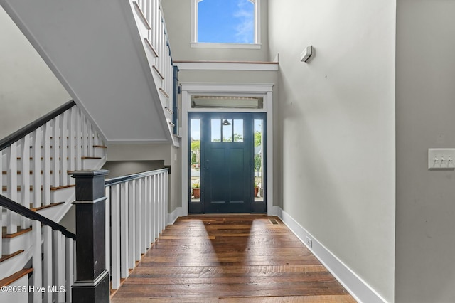 entryway featuring a towering ceiling, baseboards, stairway, and hardwood / wood-style flooring
