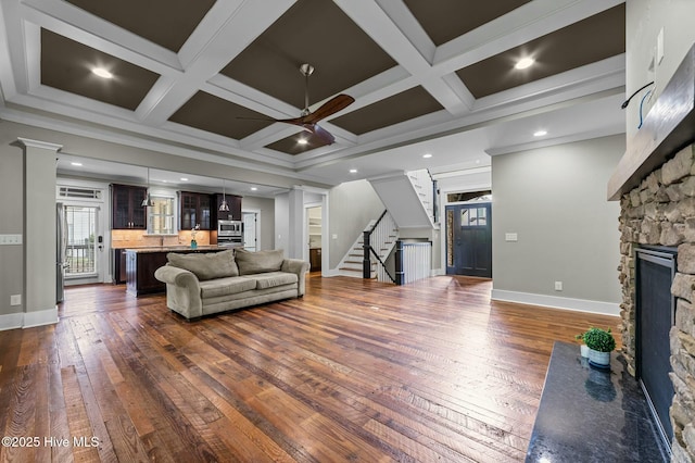 living room with ceiling fan, a fireplace, dark wood-style flooring, stairs, and baseboards