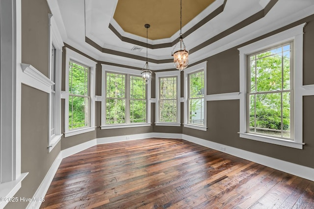 spare room featuring a tray ceiling, ornamental molding, visible vents, a chandelier, and hardwood / wood-style floors