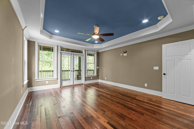 spare room with baseboards, a raised ceiling, crown molding, hardwood / wood-style floors, and ceiling fan