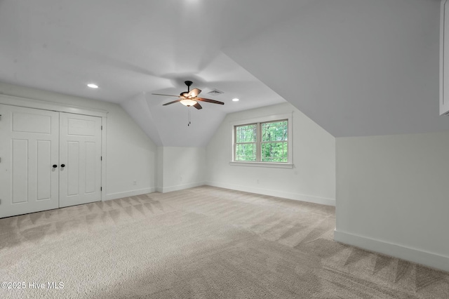 additional living space with baseboards, visible vents, lofted ceiling, light colored carpet, and ceiling fan