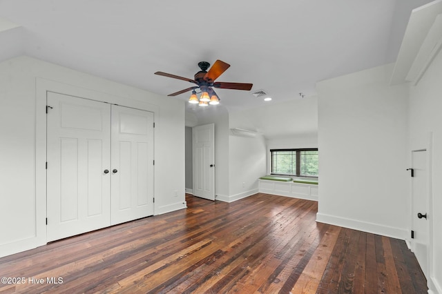 unfurnished bedroom with a closet, baseboards, visible vents, lofted ceiling, and hardwood / wood-style flooring