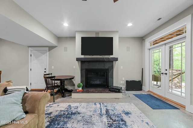 living area featuring a glass covered fireplace, recessed lighting, concrete floors, and baseboards