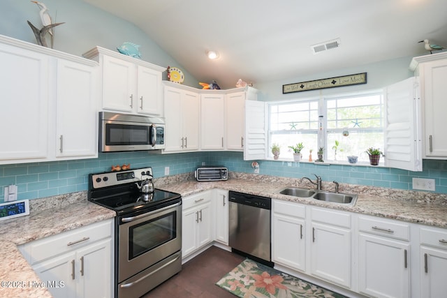 4238 Cherry Laurel Ln SE, Southport, NC 28461 - kitchen with stainless steel appliances, vaulted ceiling, white cabinets, backsplash, and dark wood-style flooring