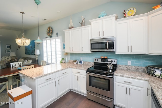 4238 Cherry Laurel Ln SE, Southport, NC 28461 - kitchen with stainless steel appliances, a peninsula, white cabinetry, dark wood-style floors, and vaulted ceiling