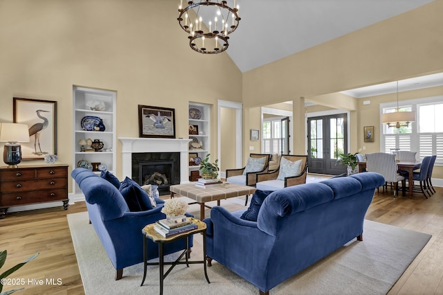 3722 White Cliffs Dr, Castle Hayne, NC 28429 - living area featuring high vaulted ceiling, light wood-style flooring, built in shelves, a chandelier, and a tiled fireplace