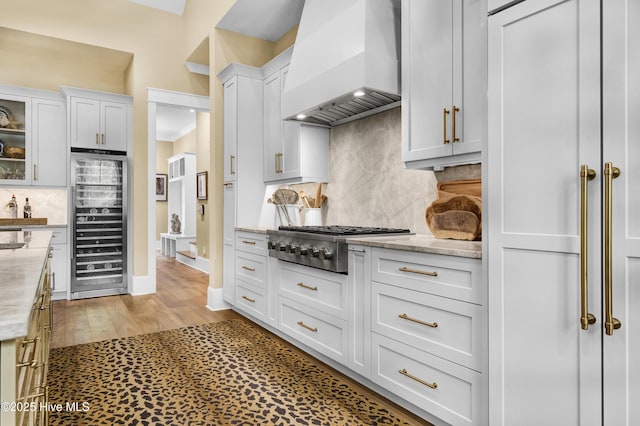 3722 White Cliffs Dr, Castle Hayne, NC 28429 - kitchen featuring wall chimney exhaust hood, beverage cooler, stainless steel gas stovetop, tasteful backsplash, and white cabinetry