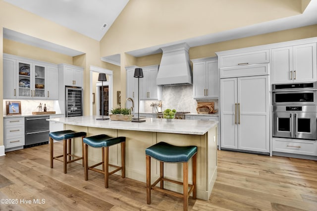 3722 White Cliffs Dr, Castle Hayne, NC 28429 - kitchen with paneled refrigerator, custom exhaust hood, wine cooler, stainless steel double oven, and a breakfast bar area