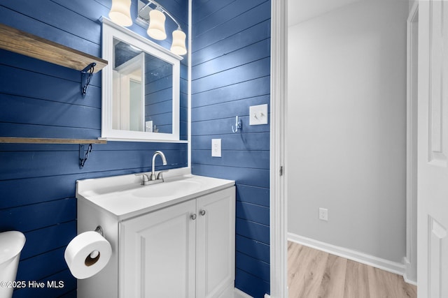 bathroom with vanity, wood finished floors, and wooden walls