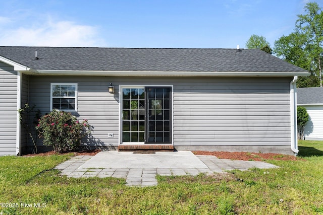 back of property featuring roof with shingles, a yard, and a patio