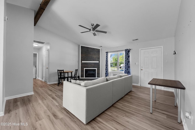 living room featuring visible vents, vaulted ceiling with beams, light wood-type flooring, a fireplace, and ceiling fan