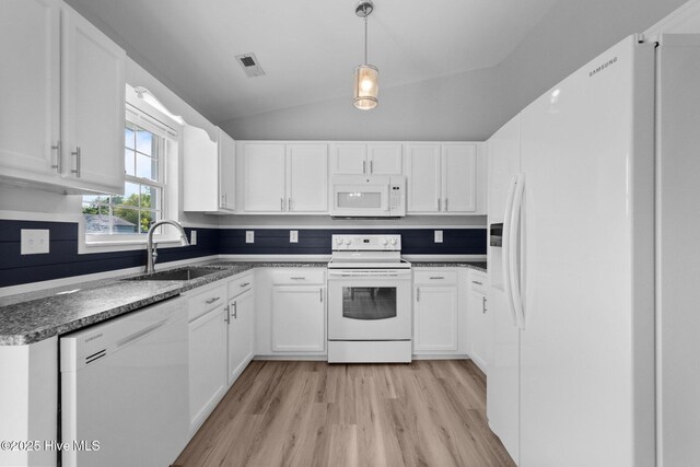 kitchen with a sink, light wood-type flooring, dark countertops, visible vents, and white appliances