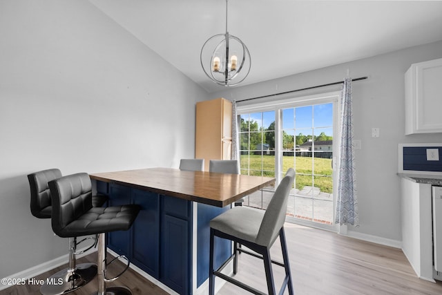dining room with light wood-style floors, baseboards, and a notable chandelier