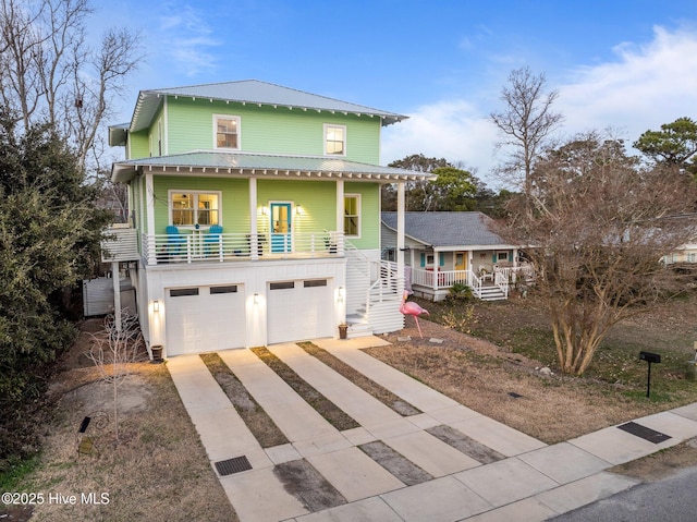 view of front facade with metal roof, stairs, concrete driveway, covered porch, and a garage