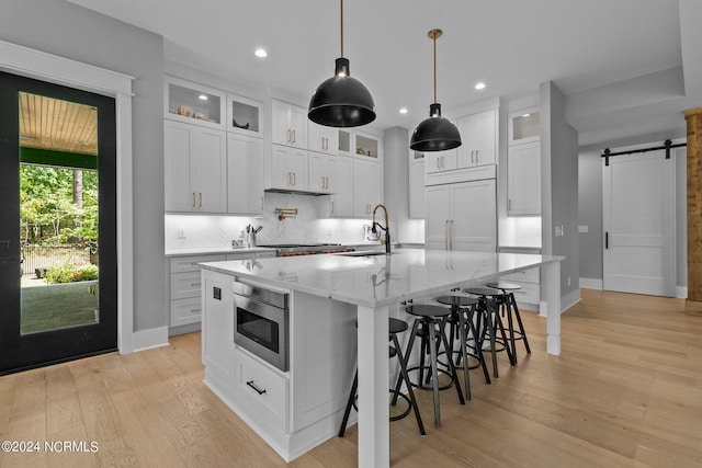 kitchen with tasteful backsplash, a barn door, recessed lighting, light wood-style floors, and built in appliances