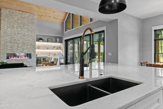 interior space featuring a wealth of natural light, a sink, and light stone counters