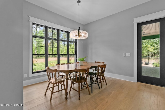 dining area with baseboards, light wood-style floors, and a notable chandelier