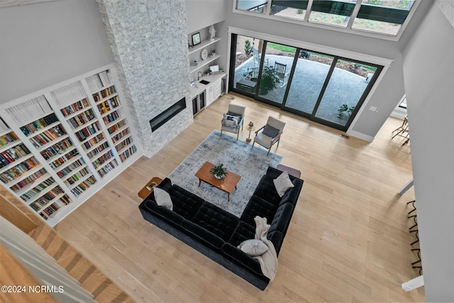 living room featuring baseboards, a large fireplace, wood finished floors, and a towering ceiling