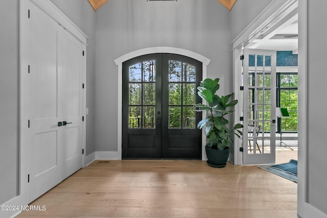 foyer featuring arched walkways, wood finished floors, a high ceiling, and french doors