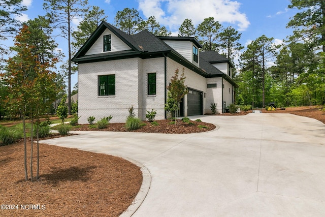view of side of property with driveway, brick siding, and a garage