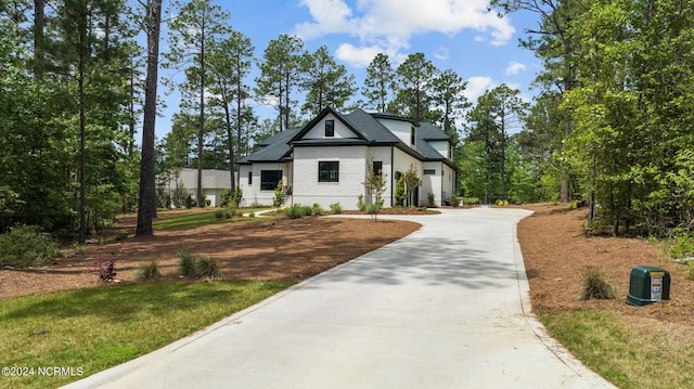 modern inspired farmhouse with a front lawn and driveway