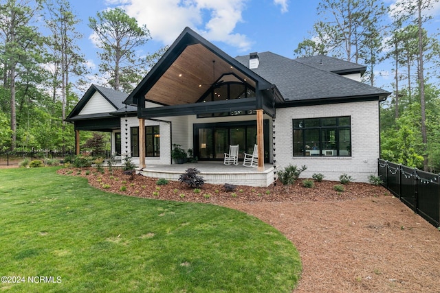rear view of property featuring fence, a yard, ceiling fan, a patio area, and brick siding