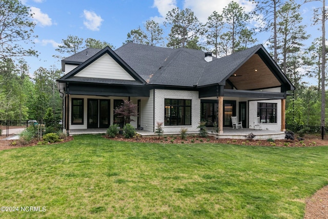 rear view of house featuring a patio area, a yard, and a shingled roof