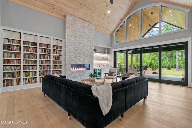 living room featuring high vaulted ceiling, wooden ceiling, a stone fireplace, and hardwood / wood-style floors