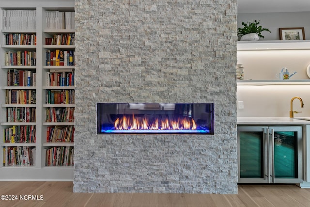 interior details featuring a sink, wood finished floors, a fireplace, wet bar, and wine cooler