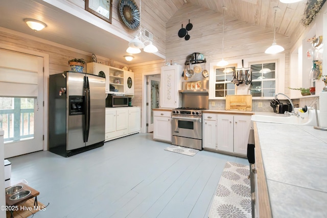 42 Brite Ln, Oriental, NC 28571 - kitchen with open shelves, wood walls, white cabinets, stainless steel appliances, and a sink