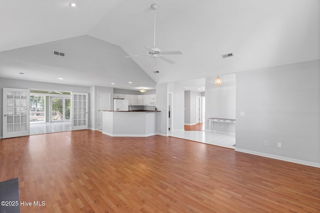 unfurnished living room featuring high vaulted ceiling, light wood-type flooring, a ceiling fan, visible vents, and baseboards