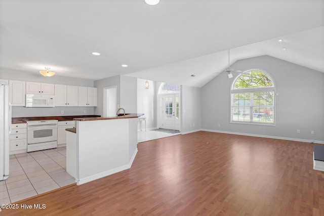 kitchen with white cabinets, dark countertops, white appliances, light wood-style floors, and lofted ceiling