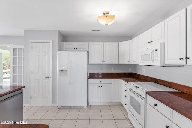 kitchen featuring light tile patterned floors, dark countertops, white appliances, and white cabinets