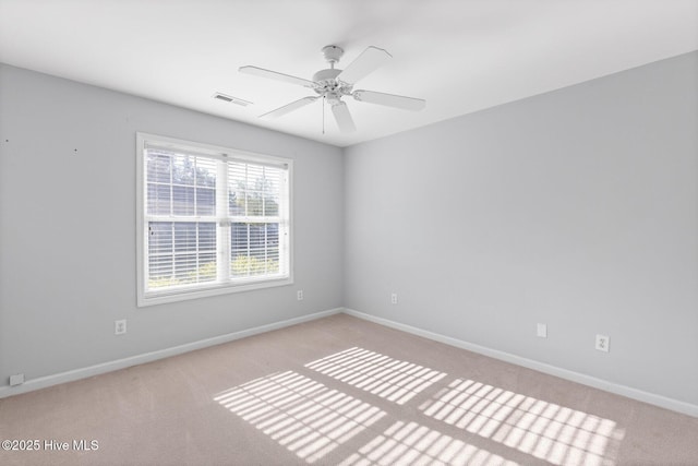 spare room with visible vents, light colored carpet, baseboards, and a ceiling fan