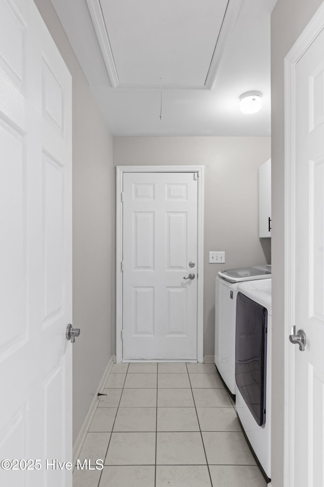 laundry room with separate washer and dryer, light tile patterned flooring, attic access, baseboards, and cabinet space