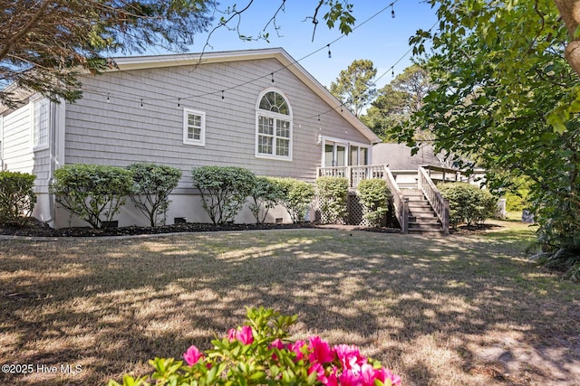view of side of property featuring a yard, a wooden deck, and stairway