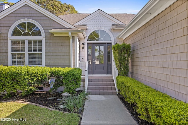 view of exterior entry featuring roof with shingles