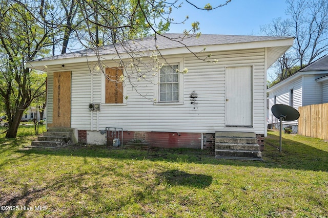 304 Ambler Ave, Rocky Mount, NC 27801 - rear view of house featuring entry steps, fence, a shingled roof, and a lawn