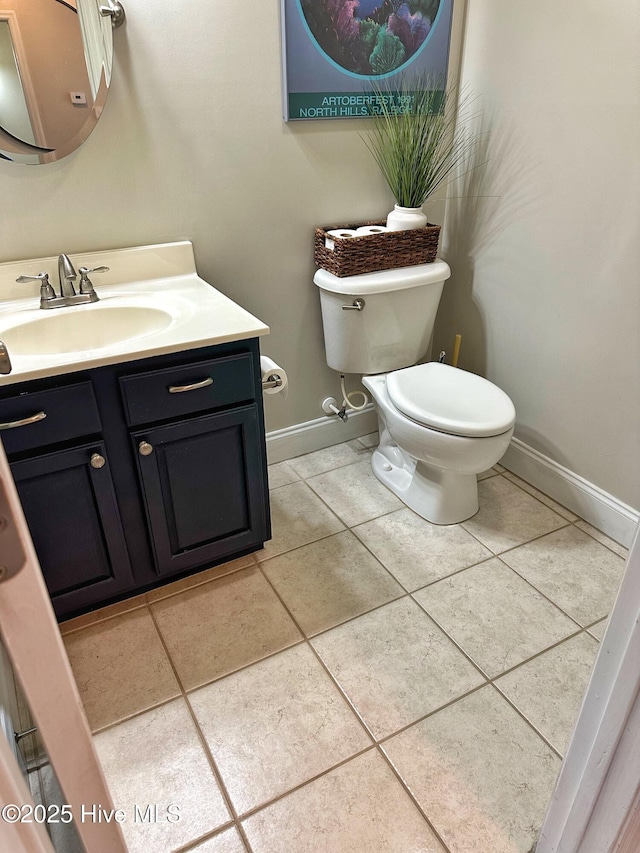 bathroom with baseboards, tile patterned flooring, toilet, and vanity