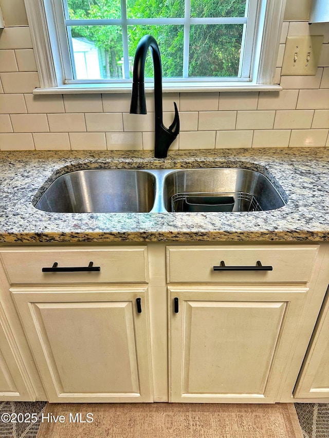 room details featuring light stone countertops, decorative backsplash, and a sink