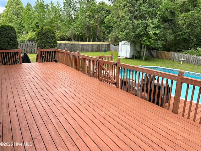 wooden deck featuring a lawn, an outdoor structure, a fenced backyard, and a shed
