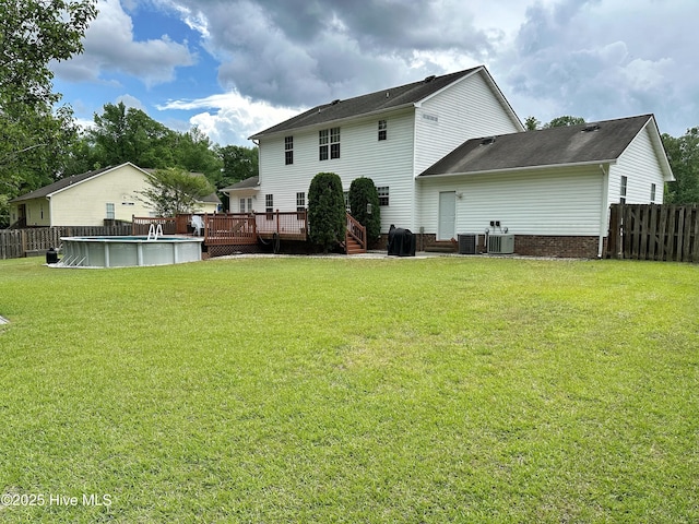 back of house featuring fence, a wooden deck, central AC unit, and an outdoor pool