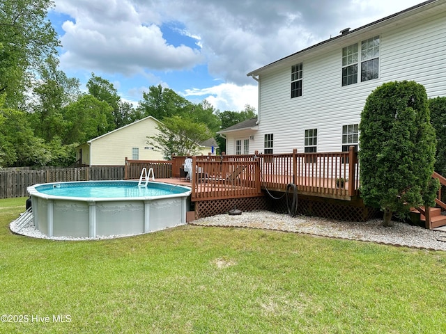 rear view of property with a fenced in pool, a lawn, fence, and a wooden deck