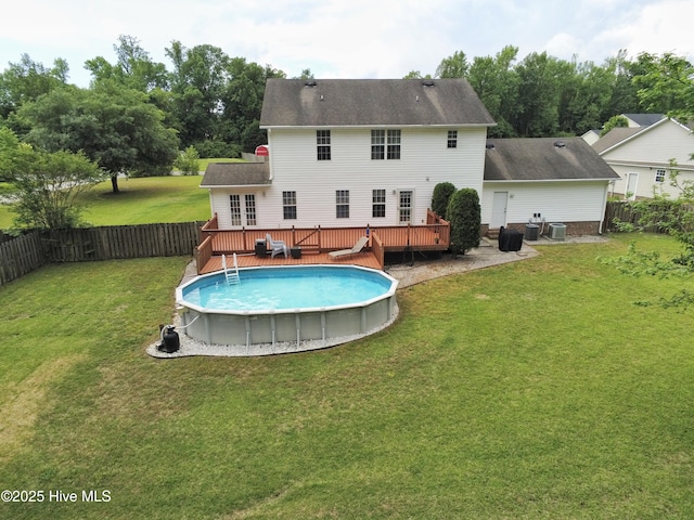 rear view of property featuring a lawn, a deck, a fenced in pool, and a fenced backyard