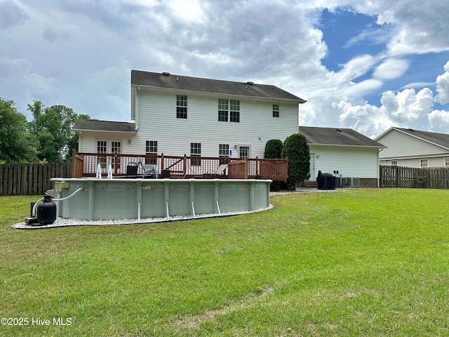 rear view of house with a fenced in pool, a fenced backyard, a wooden deck, and a yard