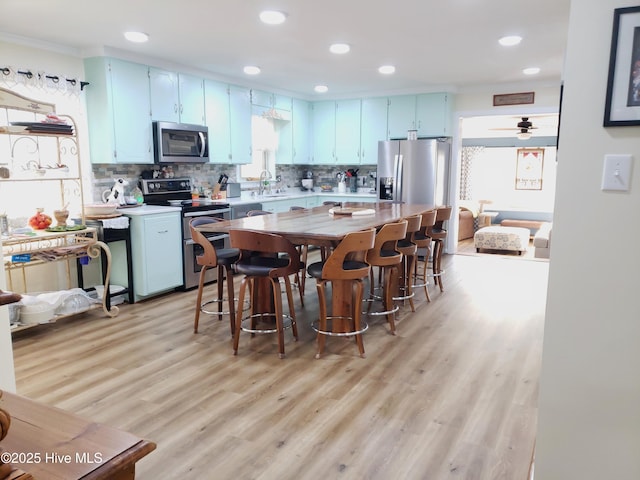 504 E S St, Fremont, NC 27830 - kitchen featuring appliances with stainless steel finishes, blue cabinets, light wood finished floors, light countertops, and decorative backsplash