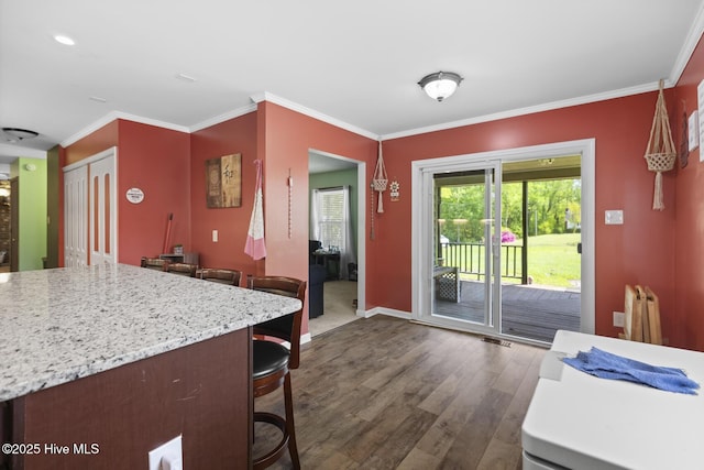 kitchen featuring baseboards, crown molding, and dark wood-style floors
