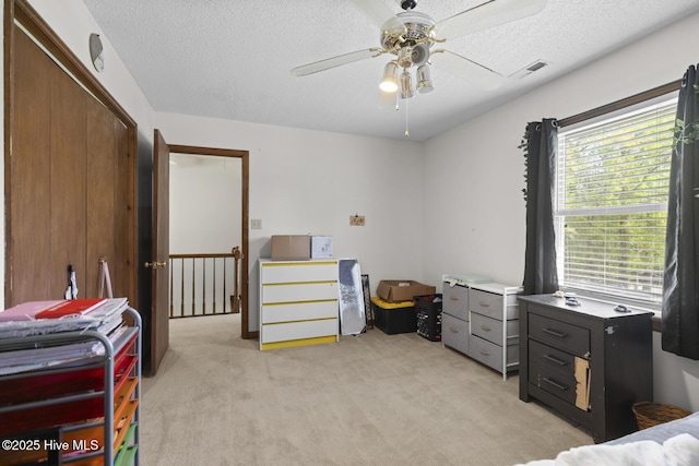 bedroom with a textured ceiling, visible vents, light colored carpet, and multiple windows